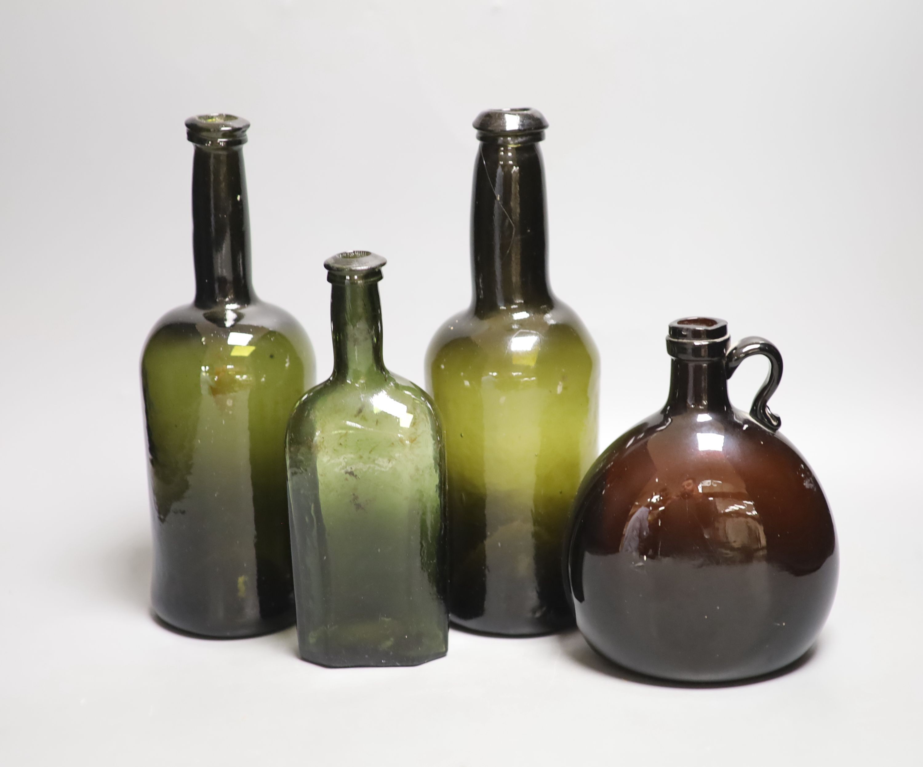Two English dark green glass wine bottles, late 18th century, a Victorian amber glass hock jug and an early 19th century dark green glass small bottle, tallest 26.5cm (4)